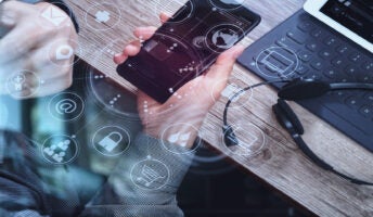 Person on mobile with laptop in background