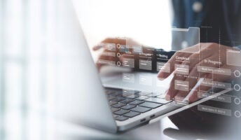 Person typing on keyboard with project management software on display