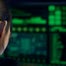 Cyberhacker looks at green text on a computer