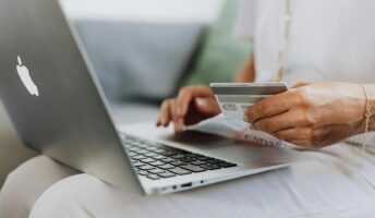 A person holds a credit card in front of a laptop